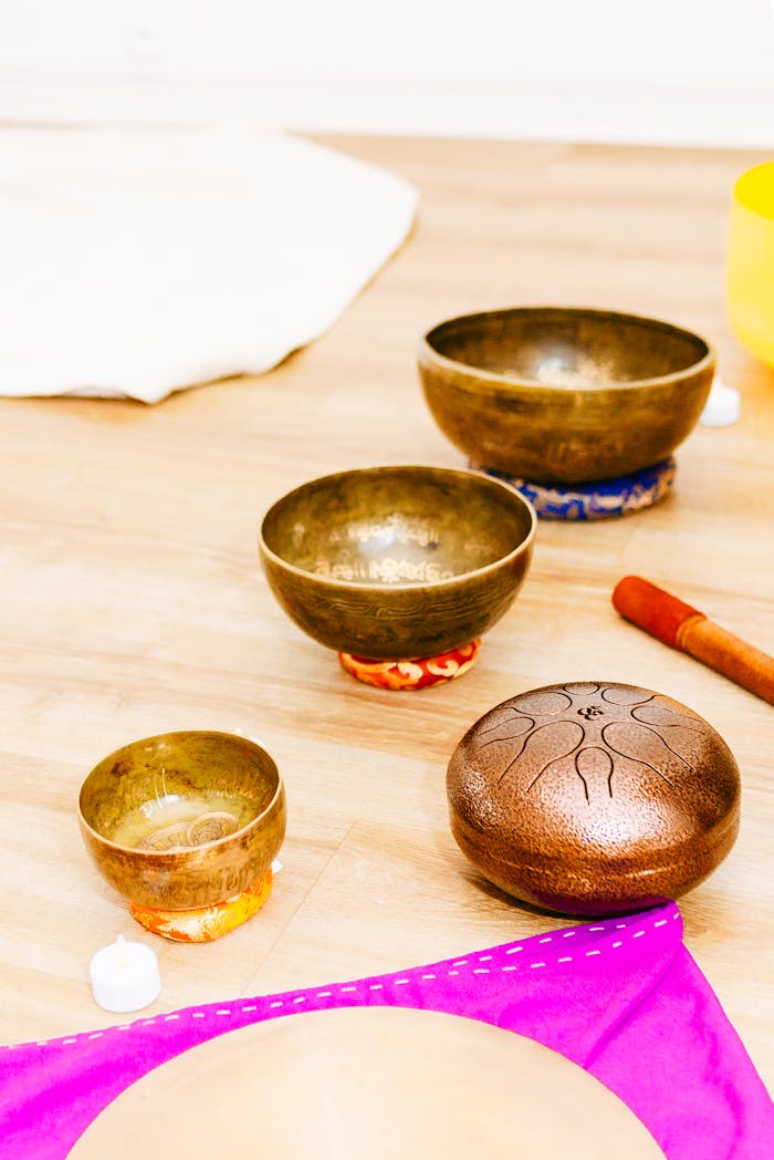 A serene arrangement of Tibetan singing bowls and mallet on a wooden floor for meditation.