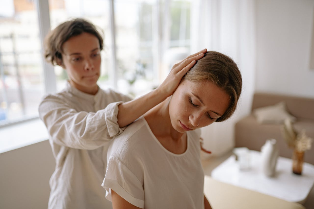 A therapist gently assists a client with a relaxation technique in a calm indoor setting.